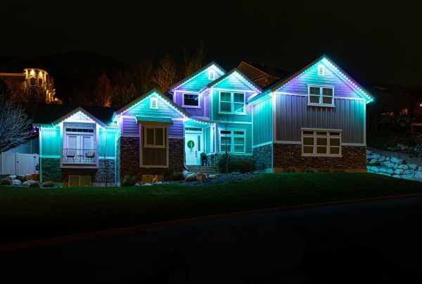 Ideas for May with Trimlight. Photo of a home with green, blue and purple lights.